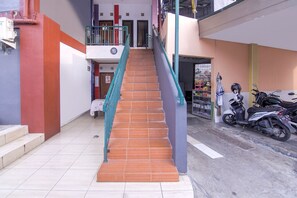 A multi-level building with a staircase, a scooter parked outside, and a door leading to a shop. - OYO 3317 Maju Jaya Homestay (Bogor)