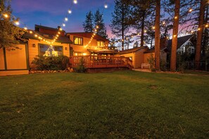 Une propriété résidentielle dotée d’une terrasse en bois, de guirlandes lumineuses et d’une pelouse.