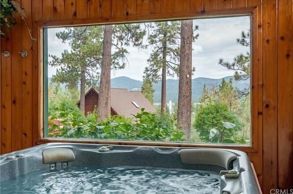 Un jacuzzi con vista a una cabaña de madera.