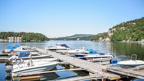A marina with multiple boats docked at wooden piers, surrounded by hills and trees. - 3 bedroom awesome home in Skjold (Skjold)