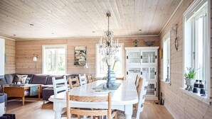 A spacious dining area with a white table and chairs, surrounded by wooden walls and a chandelier. - 3 bedroom awesome home in Skjold (Skjold)