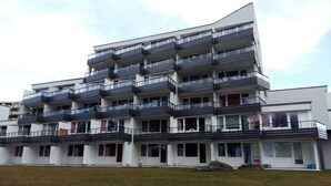Un edificio residencial de varios pisos con balcones, ventanas amplias y techo plano.