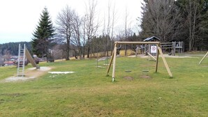 Un parque infantil con columpios, un tobogán y una estructura para escalar.