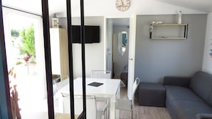 Una sala de estar moderna con una mesa blanca, un sofá gris y un televisor montado en la pared.