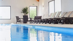 Una piscina interior con sillas de descanso y una planta en maceta.
