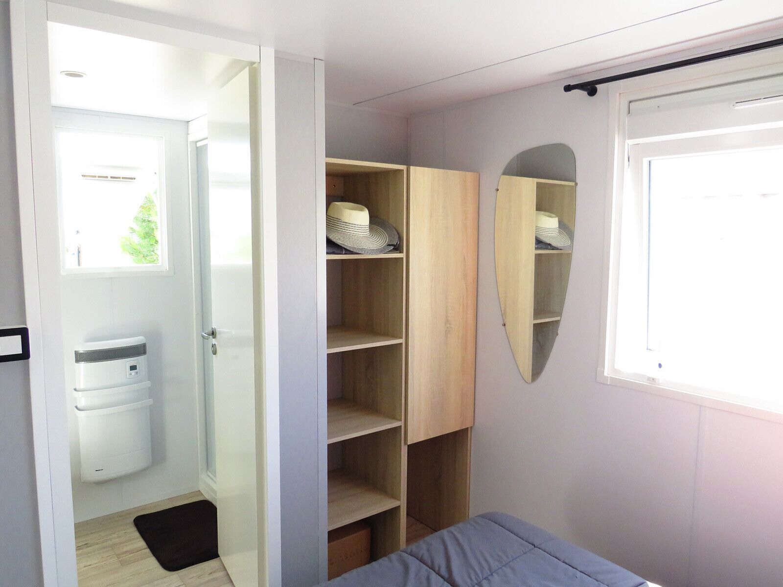 Une chambre à coucher avec un lit, une armoire, un miroir et une fenêtre.