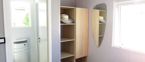 Une chambre à coucher avec un lit, une armoire, un miroir et une fenêtre.