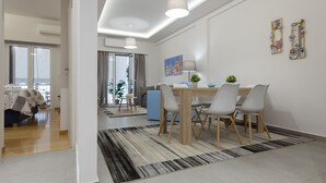 A modern living room with a dining area, featuring a sofa, a coffee table, and a dining table with chairs. - 57m² Koukaki Luxury Flat next to Acropolis & Metro (Athens)