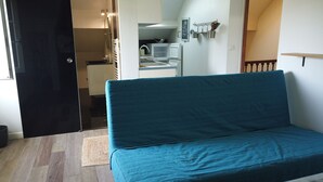 A room with a teal sofa, a small kitchenette, and a bathroom visible through an open door. - 350m from the beach - flat for 4 (Pornichet)