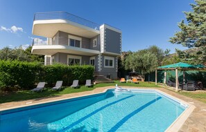 A two-story building with a swimming pool, outdoor seating, and a covered area. - 290m² Villa with Pool close to the Airport (Vari-Voula-Vouliagmeni)