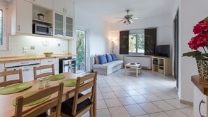 Une cuisine moderne avec des meubles blancs, un four à micro-ondes et un coin repas comprenant une table et des chaises.