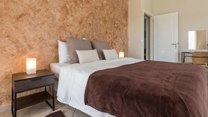 Une chambre à coucher avec un lit, des tables de chevet et un mur à la surface texturée.