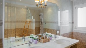 Une salle de bain avec deux lavabos, une douche et un grand miroir.
