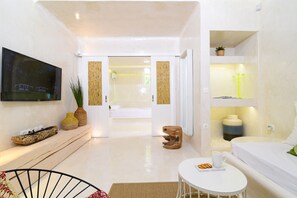 Una sala de estar moderna con un televisor de pantalla plana, un sofá, una mesa de centro y un taburete de madera.