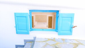 A room with a white wall and a window with blue shutters. - Mykonos 52m² Luxury Apartment Sea side Ornos (Mykonos)