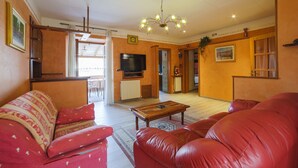 Uma sala de estar com sofás de couro vermelho, uma mesa de centro de madeira e uma televisão.