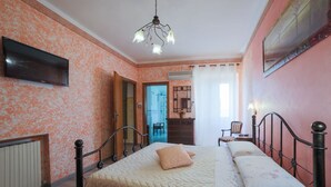Quarto com cama, televisão, guarda-roupa e banheiro visível por uma porta aberta.