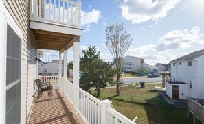A residential area with a two-story house featuring a covered porch with outdoor furniture.