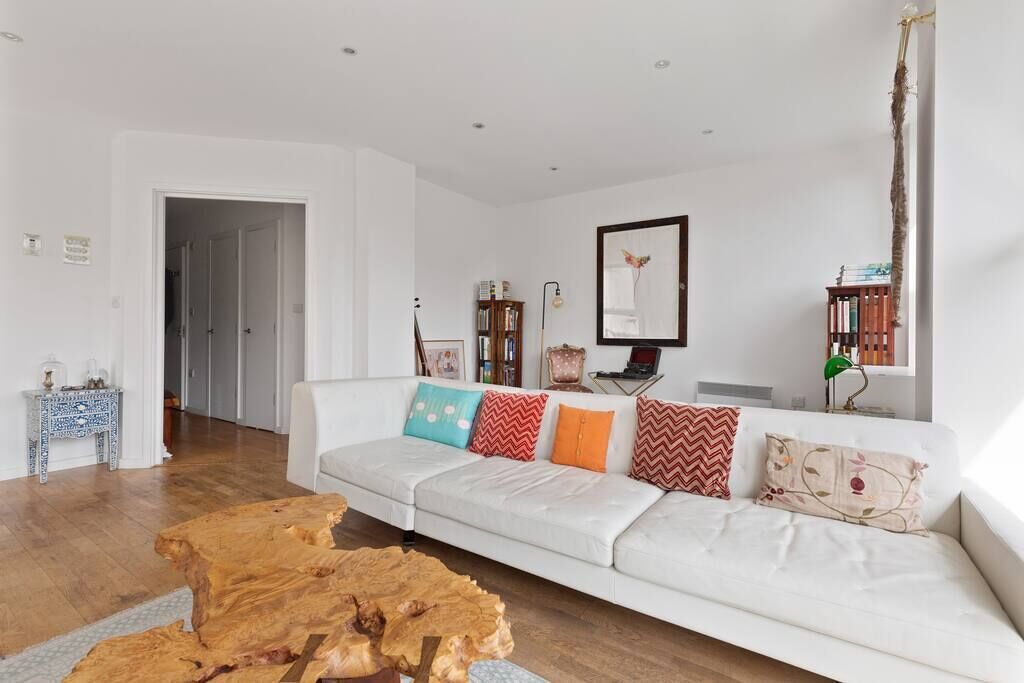 A living room with a white sofa, wooden coffee table, and a bookshelf.