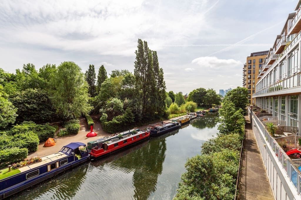 Un canal où naviguent des bateaux, bordé de verdure et entouré de bâtiments modernes.