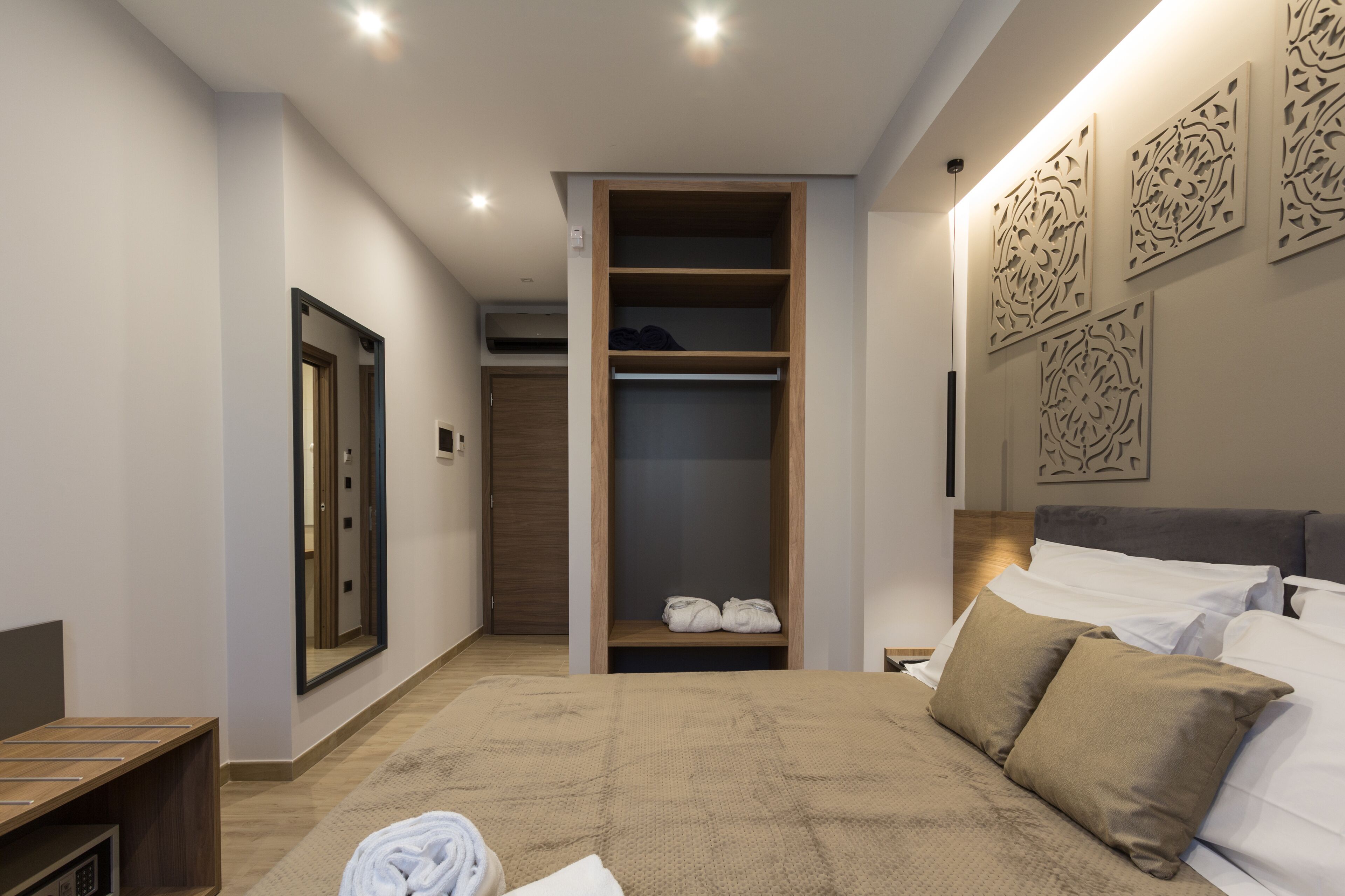 A modern bedroom with a large bed, a walk-in closet, and a mirror.