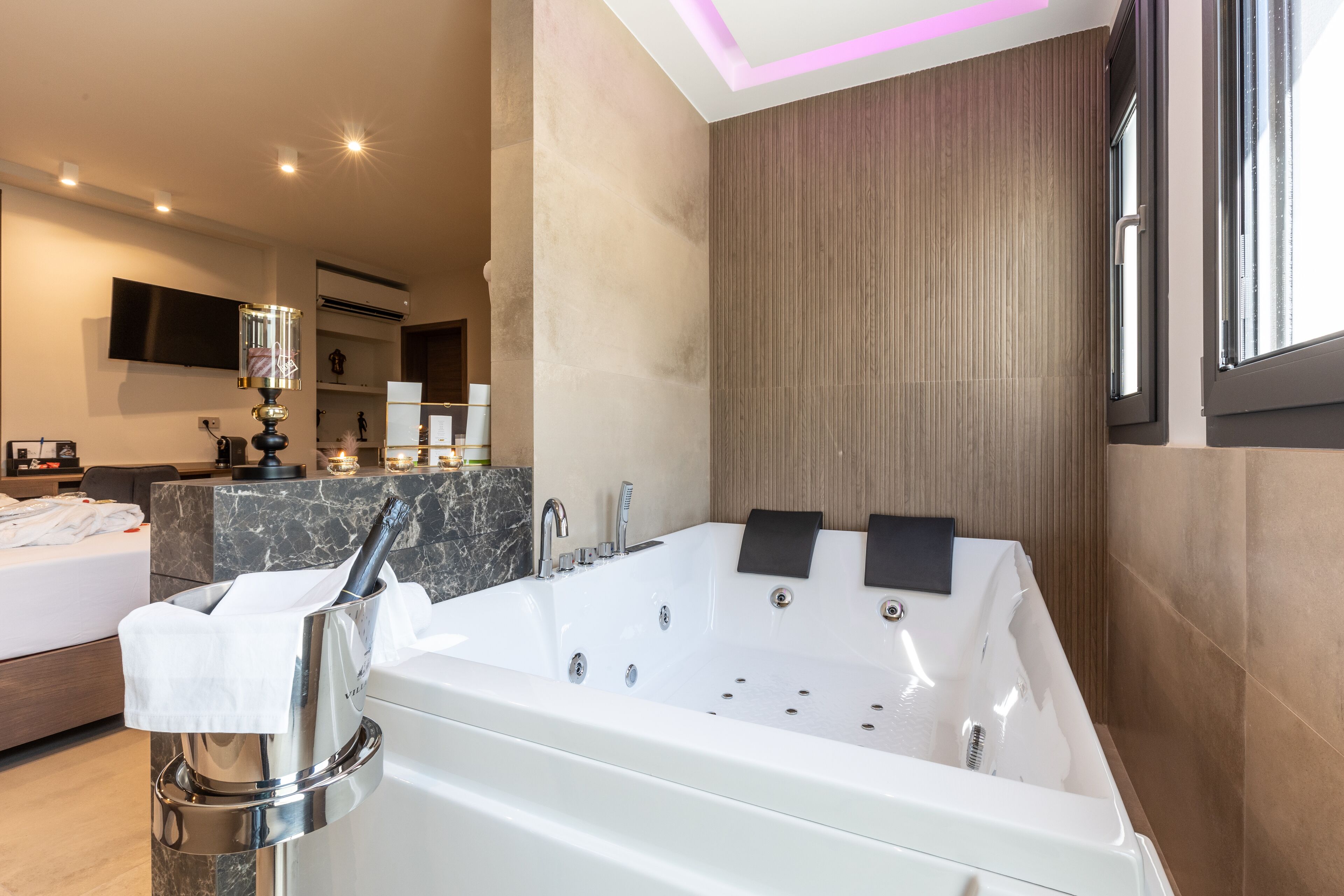 Ein modernes Badezimmer mit einer großen Badewanne, einem Waschtisch mit Spiegel und einem flachbildfernseher an der Wand.
