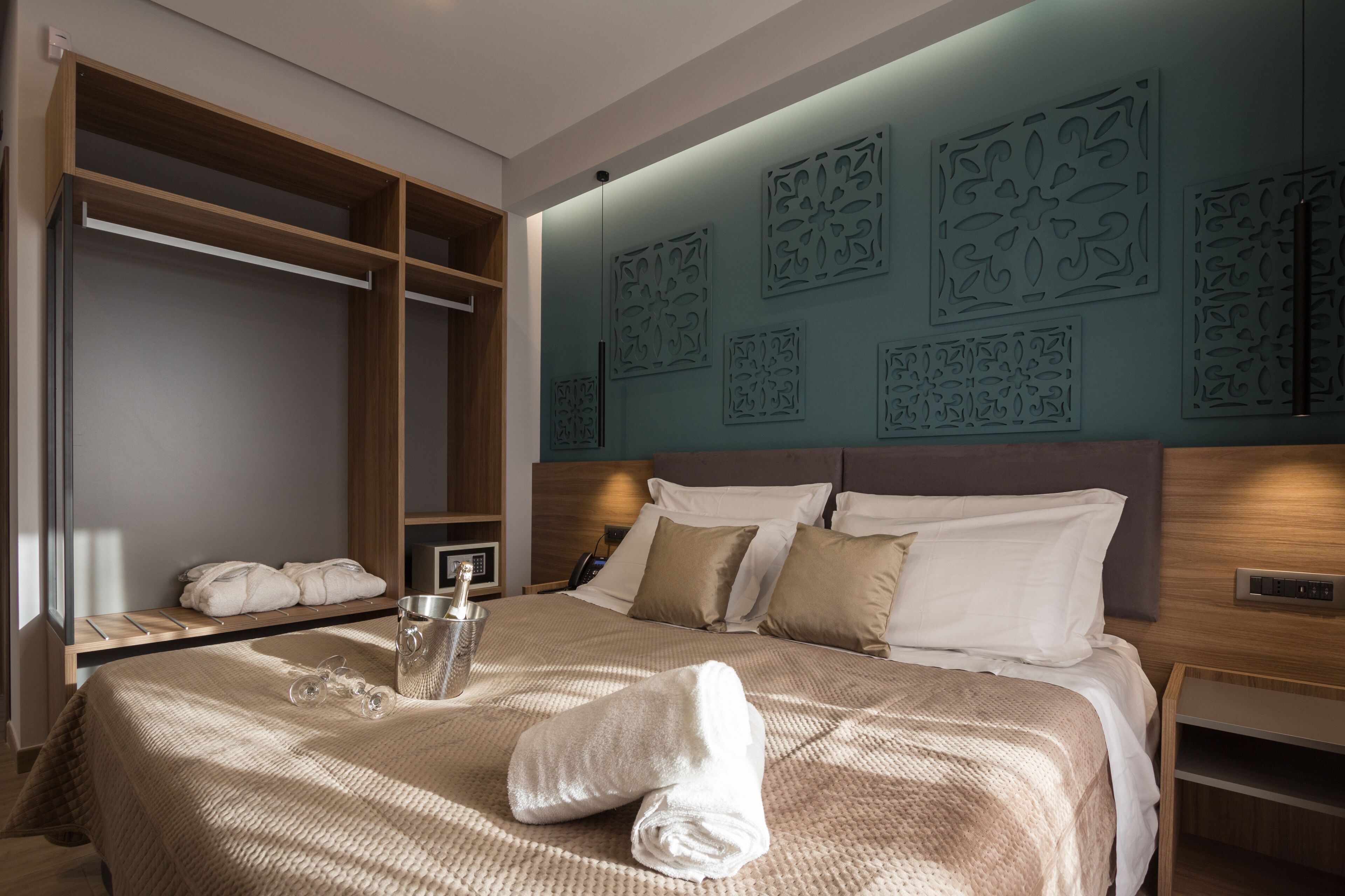 A neatly made bed with a rolled towel, a bedside table with a bottle, and a wall with decorative panels.