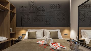 Une chambre d’hôtel avec un grand lit, une table de chevet avec un téléphone, un minibar et des panneaux décoratifs sur les murs.