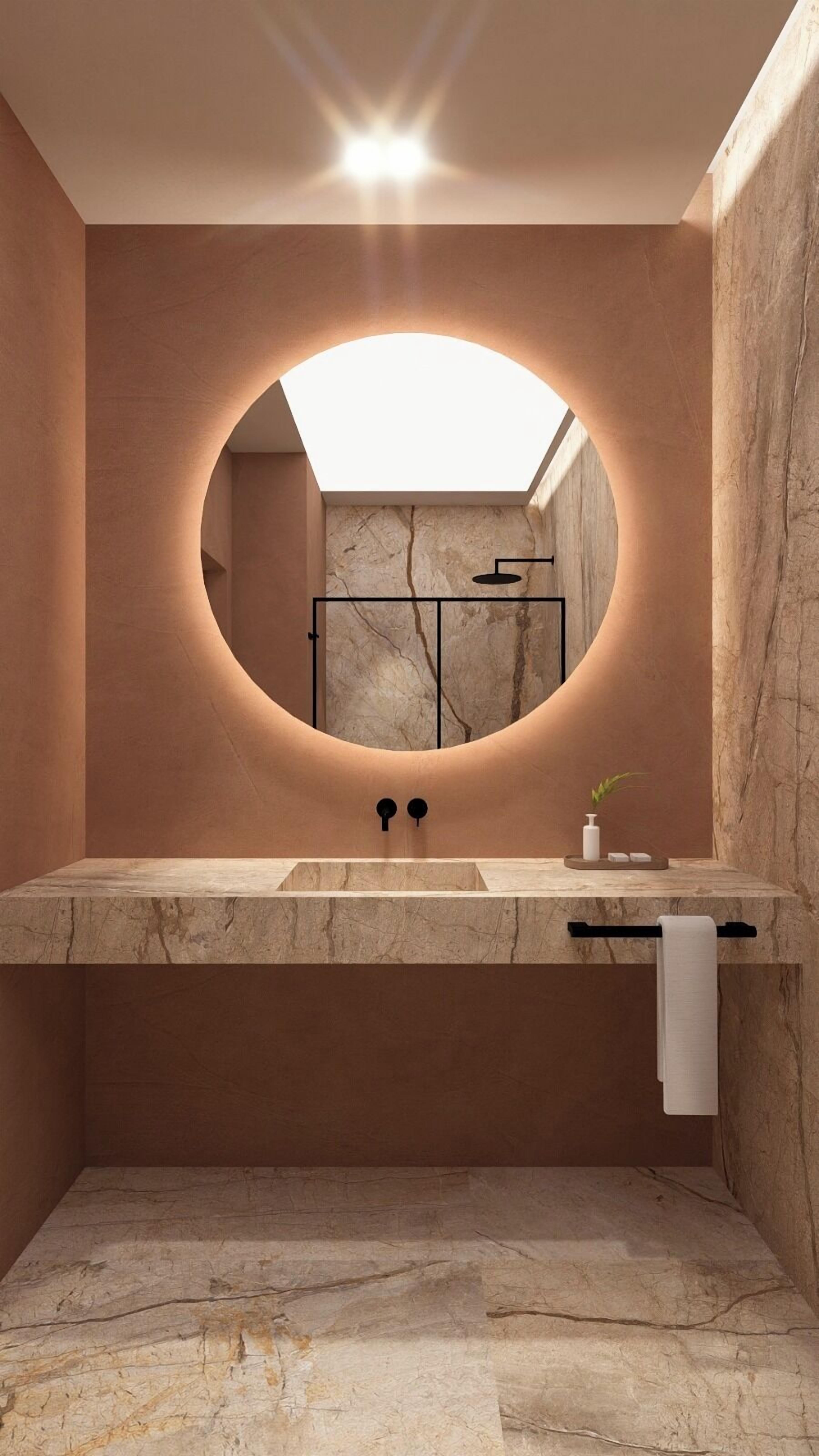 A modern bathroom with a round mirror, a sink, and a towel rack.