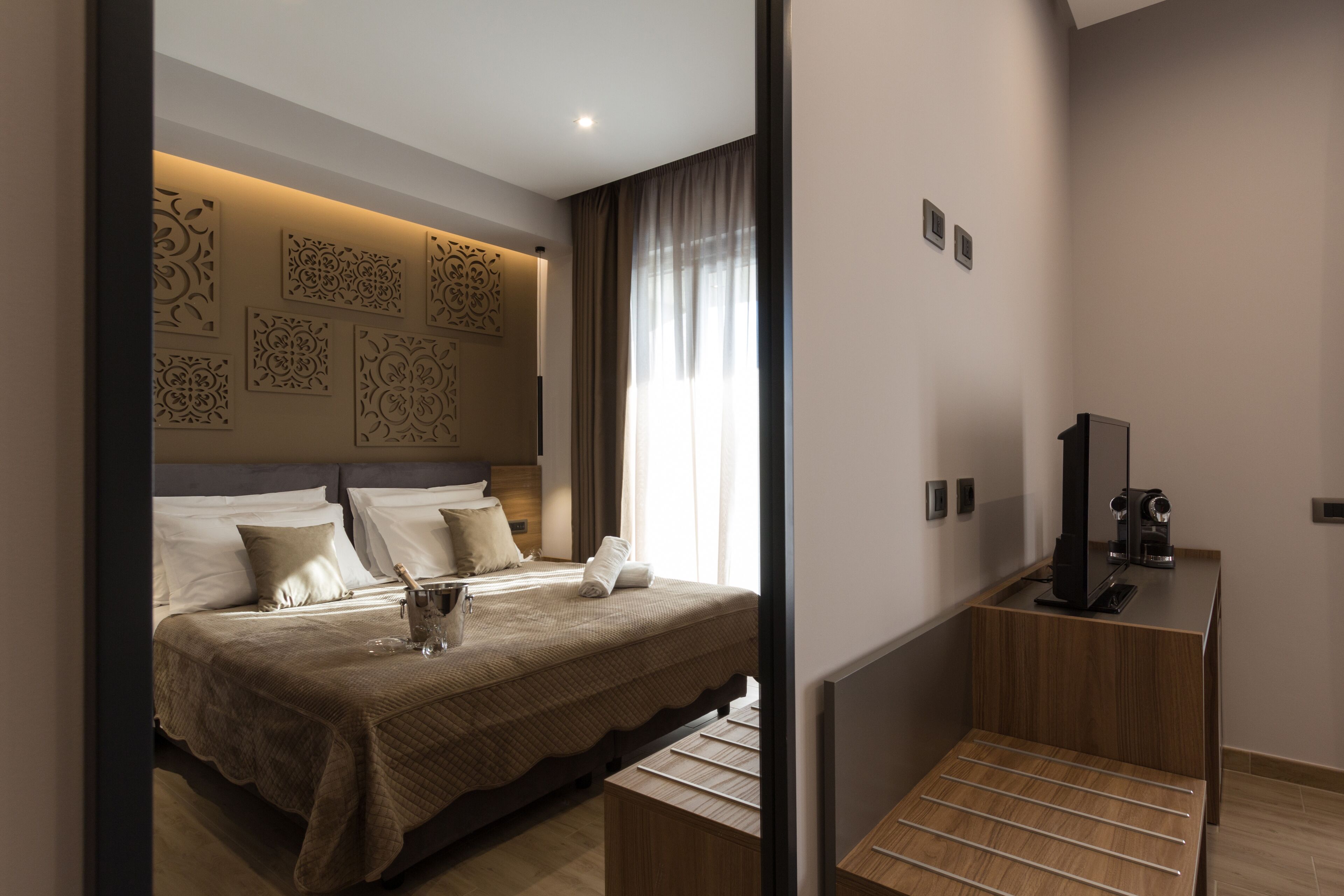 A modern hotel room with a large bed, a flat-screen TV, and a coffee machine.