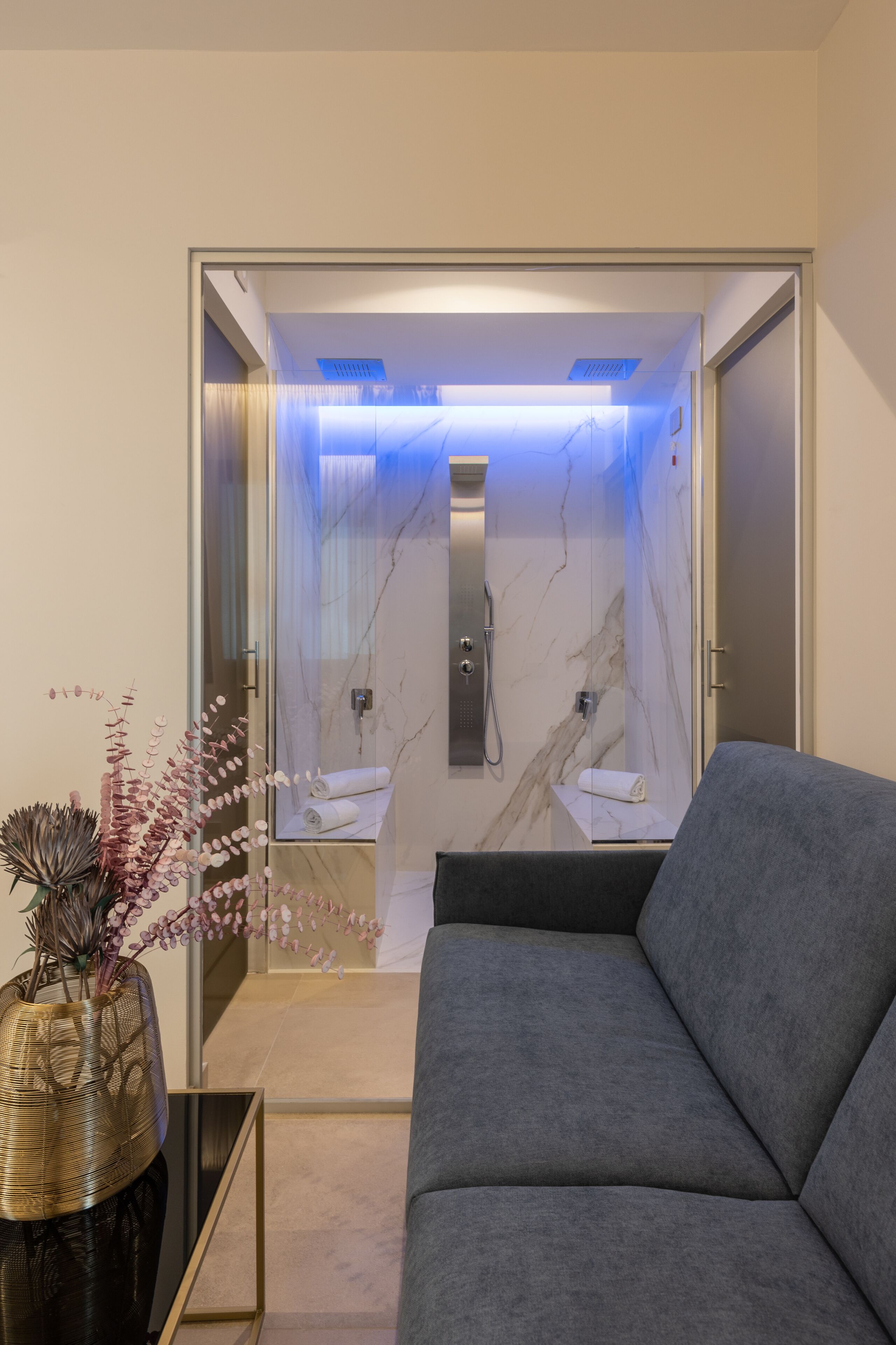 A modern bathroom with a glass enclosure, a marble shower, and a towel rack.