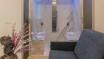 A modern bathroom with a glass enclosure, a marble shower, and a towel rack.