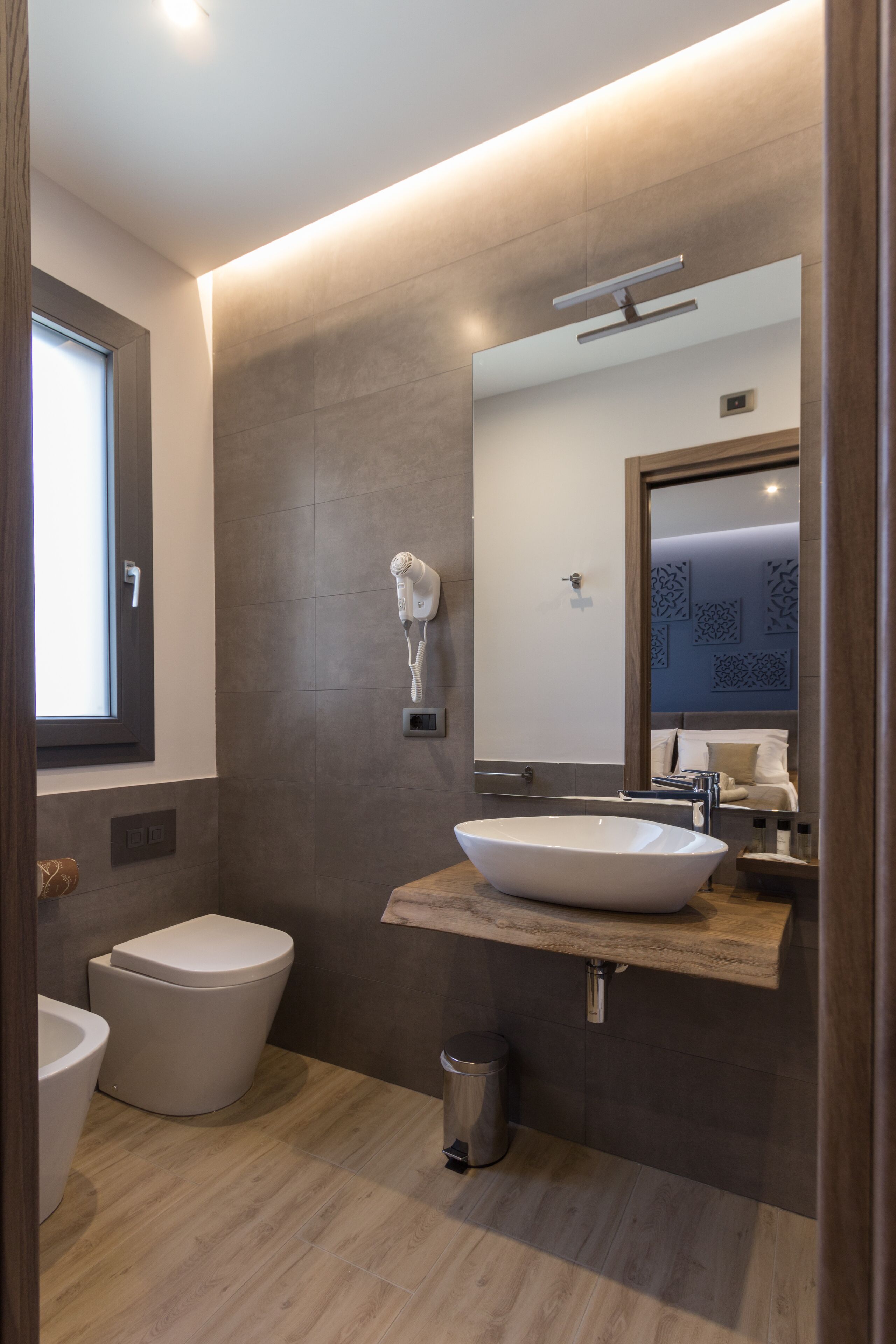 A modern bathroom with a large mirror, a vessel sink, and a toilet.
