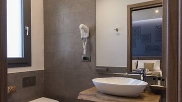 A modern bathroom with a large mirror, a vessel sink, and a toilet.