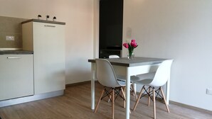 A modern kitchen with a built-in oven, a dining table with two chairs, and a vase with flowers on the table. - Ap. Annivè – Relaxation and comfort just steps from the heart of Levico Terme (Levico Terme)
