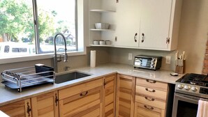 A kitchen with wooden cabinets, a stainless steel sink, a built-in oven, and a window with a view of the outside. - Ruby`s House ~ Downtown Durango (Durango)