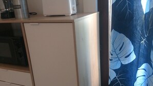 Ett litet kök med mikrovågsugn, kaffebryggare och ett litet kylskåp.