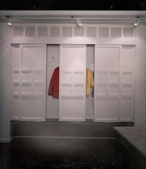 Um corredor com três portas, cada uma com um porta-roupas suspenso.