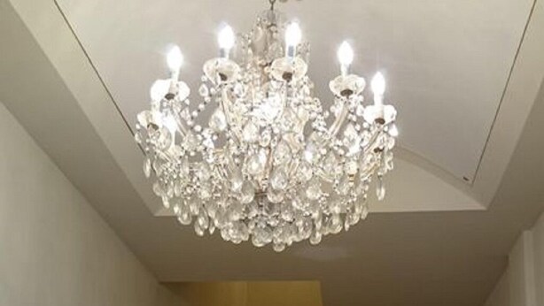 Una imponente escalera con candelabro de cristal que conduce a un pasillo luminoso.