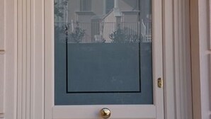 Una puerta blanca con un panel de vidrio y un pomo de latón.