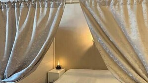 Une chambre avec un lit, des rideaux, une table de chevet et une lampe.