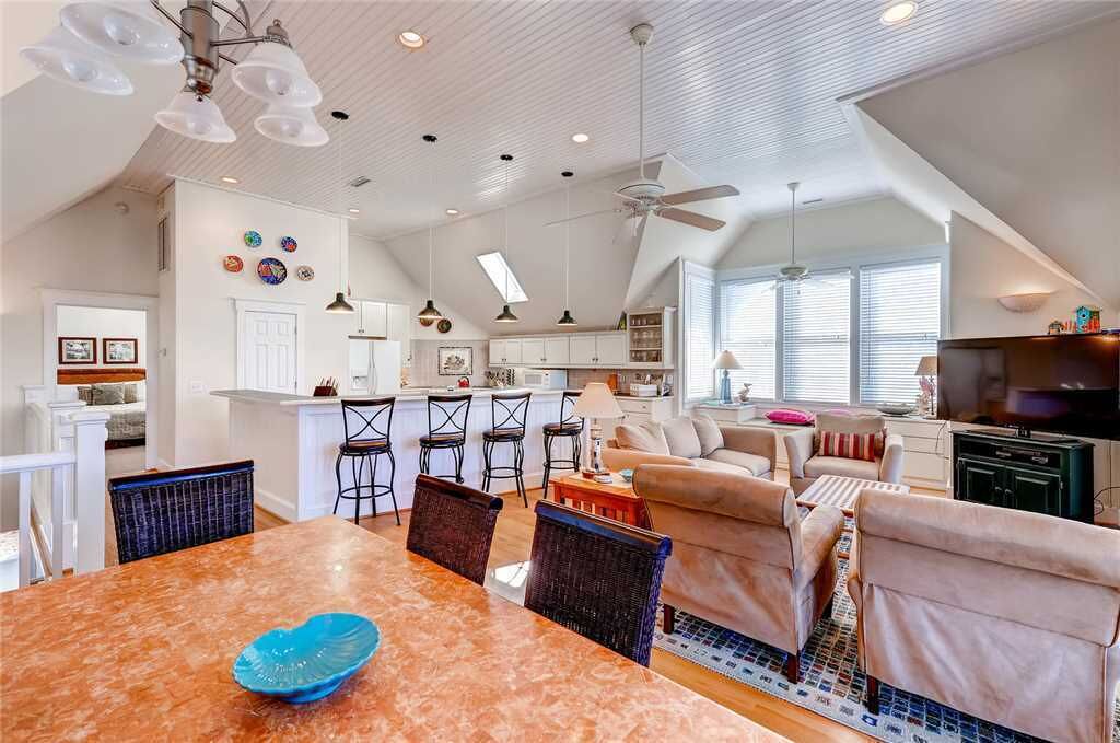 Amplia sala de estar con una mesa de comedor, sofás y una cocina al fondo.