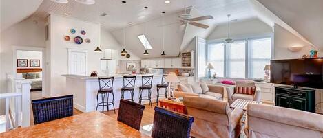 Amplia sala de estar con una mesa de comedor, sofás y una cocina al fondo.