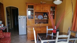 Eine kleine Küche mit Holzausstattung, einem Kühlschrank und einem Essbereich mit Tisch und Stühlen.