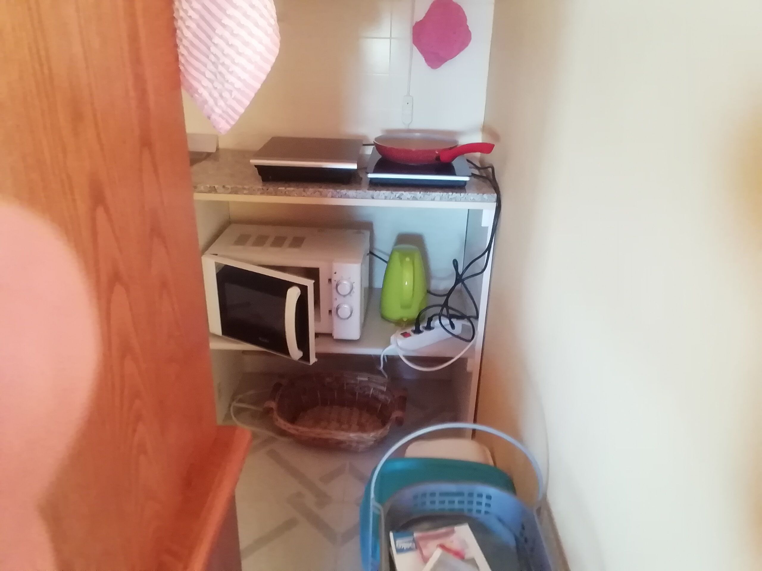 Eine Küche mit Mikrowelle, Toaster und einer roten Bratpfanne auf der Arbeitsfläche.
