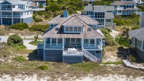 A beachfront house with a balcony, multiple windows, and a covered outdoor seating area. - Spacious Oceanfront home near golf and pool, BHI (Bald Head Island)