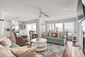 A spacious living room with a round coffee table, a green sofa, and a wicker chair.