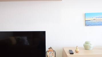 Un salón minimalista con un televisor de pantalla plana, un mueble de madera, adornos y un cuadro en la pared.