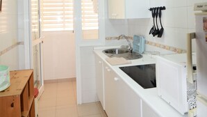 A compact kitchen with white cabinets, a microwave, a sink, and a wooden table. - - (Granadilla de Abona)