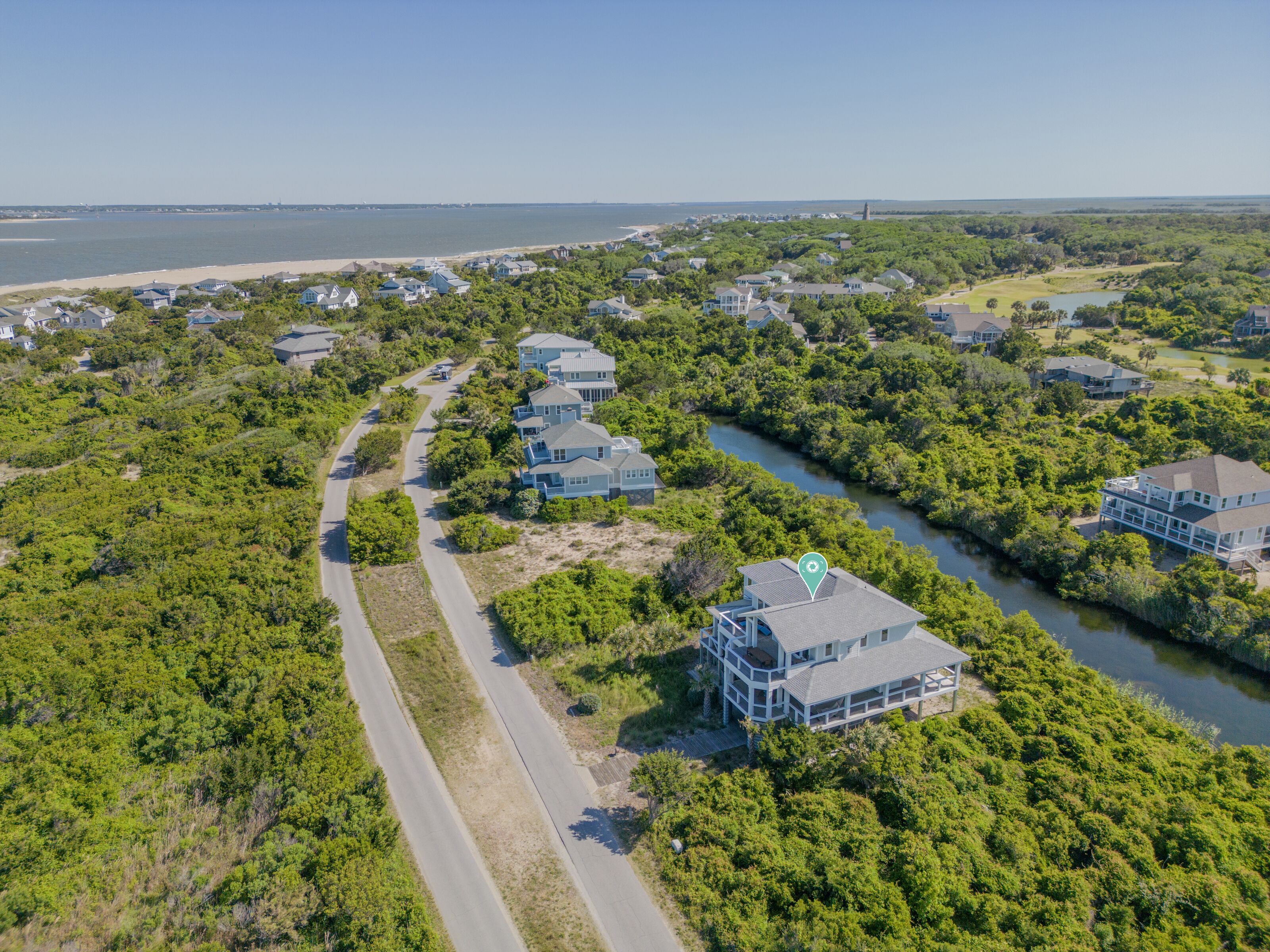 An aerial view of a residential area with houses, a river, and a beach.
